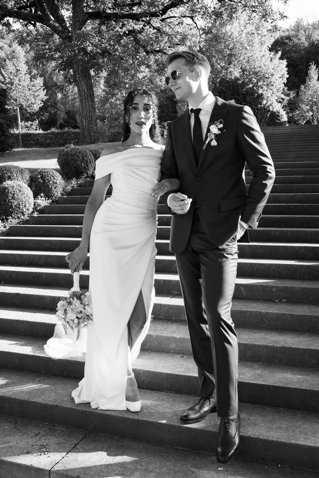 Editorial black-and-white portrait of the couple on sunlit stone steps