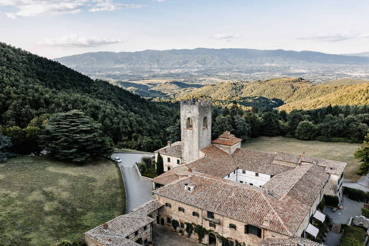 Aerial view of a medieval Tuscan monastery surrounded by wooded hills